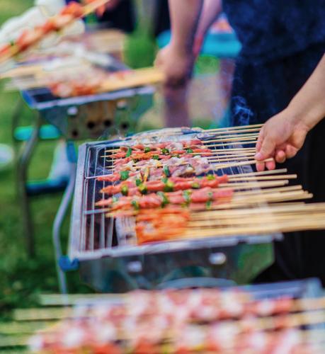 a person is cooking hot dogs on a grill at Shanyin Xijiang Rustic Luxury Resort Hotel in Bailian