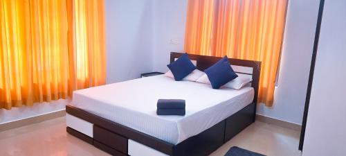 a bedroom with a bed with blue and orange curtains at Sands Villa Homestay in Wayanad