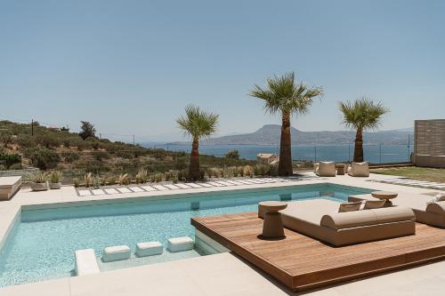 a swimming pool with chaise lounge chairs and palm trees at Villa Niolos I in Marathi
