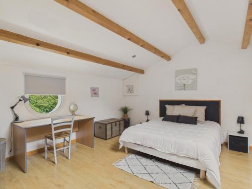 a bedroom with a bed and a desk and a window at Belle et spacieuse maison au calme pour 8 in Saint-Révérend