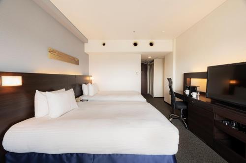 a hotel room with two beds and a flat screen tv at ANA Crowne Plaza Kumamoto New Sky by IHG in Kumamoto