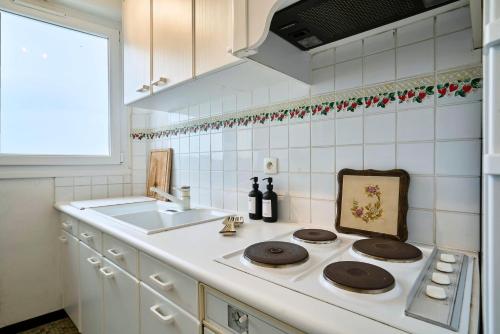 une cuisine blanche avec une cuisinière et un évier dans l'établissement Le Marin - Les Demeures d'Adrien, à Neufchâtel-Hardelot