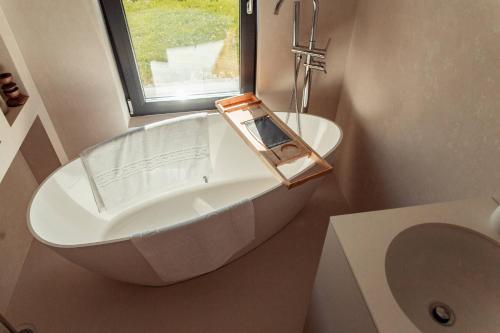 a bathroom with a tub and a toilet and a window at Amumi Lacul Bicaz - Casuta Infinity in Buhalniţa
