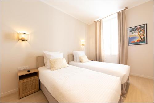 two twin beds in a room with a window at Hotel Villa Botanica in Cannes