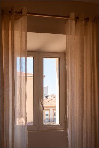 a window with curtains with a view of a building at Hotel Villa Botanica in Cannes