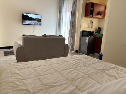 a bedroom with a bed and a couch and a television at Bukoto Stays 1 Bedroom Apartment in Kampala
