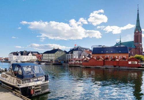 a boat is docked in a river with buildings at Down Town Arendal in Arendal