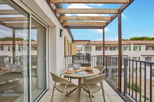 a patio with a table and chairs on a balcony at Résidence Odalys Riviera in Hyères