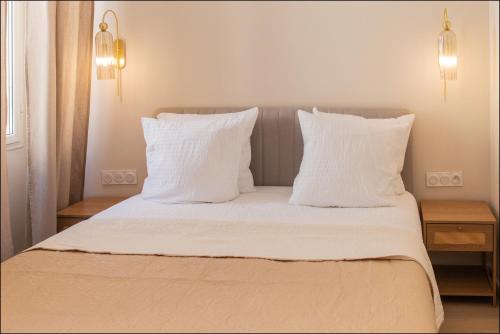 a white bed with white pillows and two night stands at Hotel Villa Botanica in Cannes