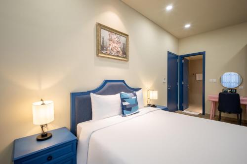 a bedroom with a large white bed and a blue nightstand at Wonderland Royal Mansions Ho Tram in Xuyên Mộc