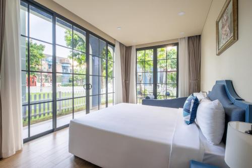 a bedroom with a large white bed and large windows at Wonderland Royal Mansions Ho Tram in Xuyên Mộc