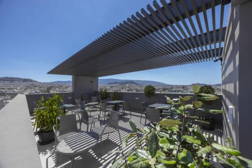 a patio with tables and chairs on a roof at Sokio Attiki Hotel, BW Premier Collection in Athens