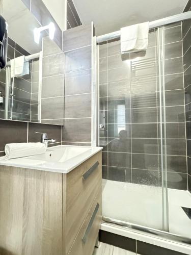 a bathroom with a sink and a glass shower at T2 Centre Riom 3 Personnes in Riom
