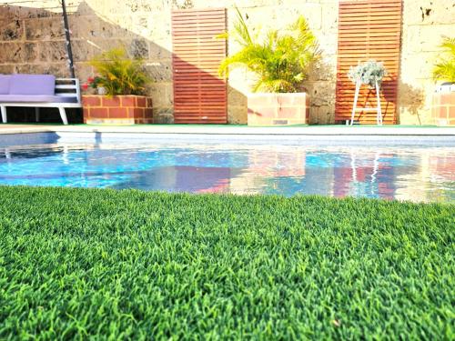 a swimming pool with blue water and green grass at Joyful living Guest Suite in Coogee