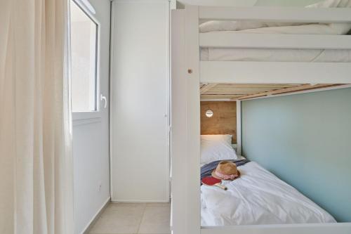 a small child sitting on a bed in a bunk room at Résidence Odalys Riviera in Hyères