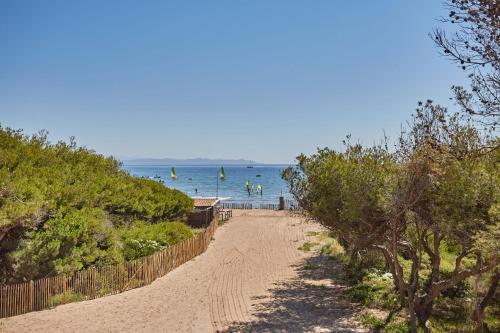 a dirt road leading to a beach with boats in the water at Résidence Odalys Riviera in Hyères