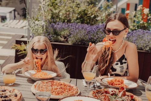 two women sitting at a table eating pizza at Hotel Linea Mare in Pobierowo