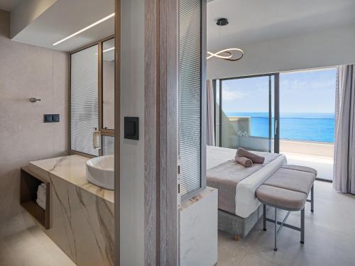 a bedroom with a bed and a bathroom with a view of the ocean at Creta Star Hotel - Adults Only in Skaleta