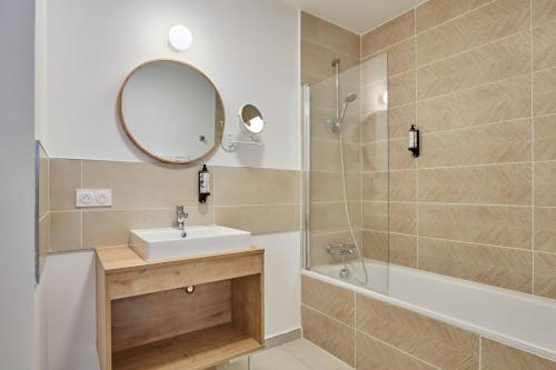 a bathroom with a sink and a mirror and a shower at Résidence Odalys Riviera in Hyères