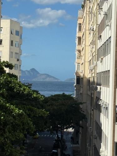 a view of the ocean from between two buildings at Espaçoso e iluminado, 1 quadra da praia, ar condicionado in Rio de Janeiro