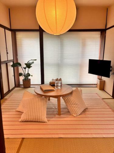 a living room with a table and a tv at MINI HOTEL totonoi ロウリュ式サウナのある静かな平屋 in Shimonoseki