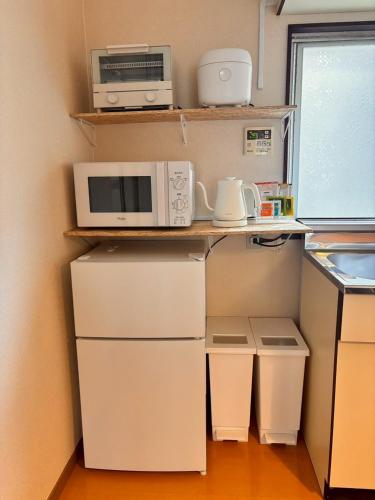a kitchen with a microwave and appliances on shelves at MINI HOTEL totonoi ロウリュ式サウナのある静かな平屋 in Shimonoseki