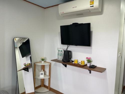 a room with a tv on a wall with a mirror at ระเบียงเลเกาะลิบง โฮมสเตย์ in Ko Libong