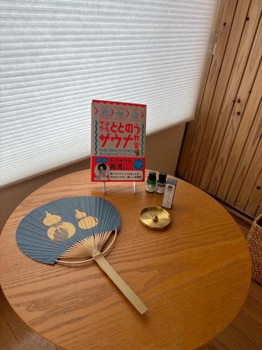 a wooden table with a book and a fan on it at MINI HOTEL totonoi ロウリュ式サウナのある静かな平屋 in Shimonoseki