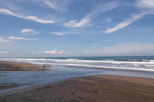 a person standing in the water on a beach at Authentic beachfront Villa Owl in Krambitan