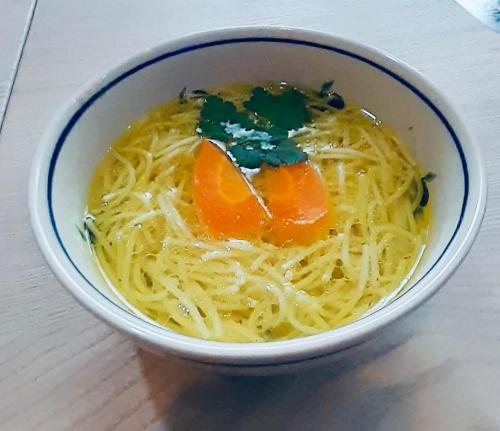a bowl of pasta with carrots and greens on a table at Jagodowy Ski&Spa DeLux apartamenty z widokiem na góry,4km od Zieleniec Ski Arena Podgrzewany basen zewnętrzny latem,bilard,Wi-Fi w cenie Restauracja,balia,sauna na miejscu in Lasowka