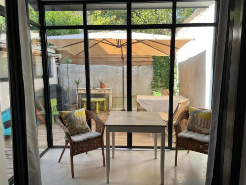 un patio avec une table, des chaises et un parasol dans l'établissement Folie sur Cour à Palavas-les-Flots 3 etoiles, à Palavas-les-Flots