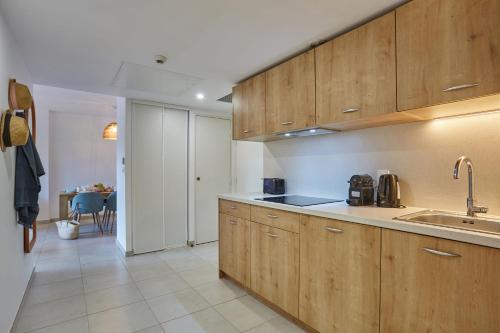 a kitchen with wooden cabinets and a sink at Résidence Odalys Riviera in Hyères
