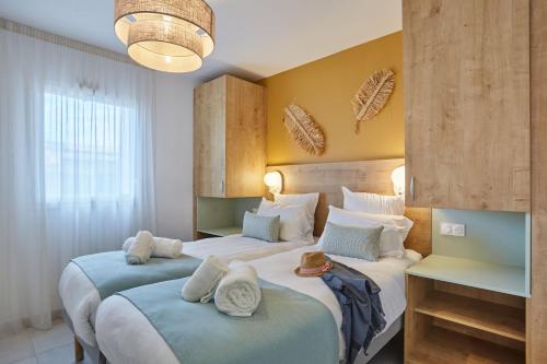 two beds in a hotel room with towels on them at Résidence Odalys Riviera in Hyères