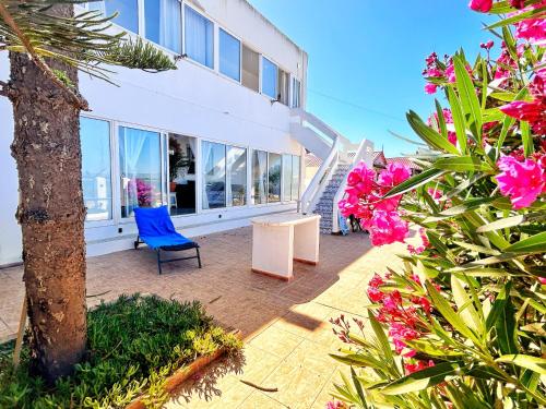 a building with a blue chair and some flowers at Lazaro Beach House in Faro