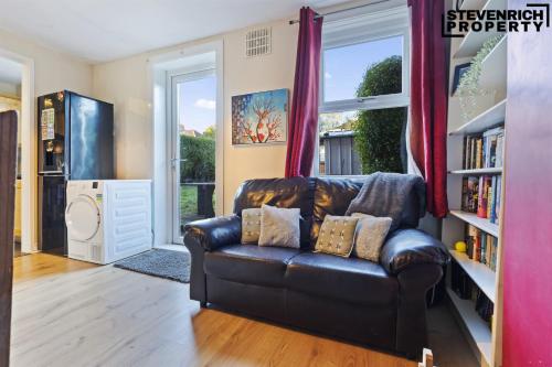 a living room with a leather couch and a book shelf at Group Stays, 4 Bedroom, Spacious Home in BS4, Van & Car Parking, Sleeps 7 in Bristol
