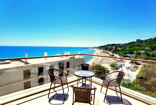 a balcony with three chairs and a table and the ocean at Cabacum Pleasure Beachfront Apartments in Varna City