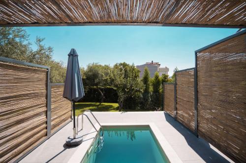 een buitenzwembad met parasol en hek bij Octo Villas Complex in Iraklitsa