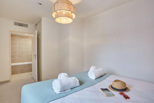 a bedroom with a bed with towels and a hat on it at Résidence Odalys Riviera in Hyères