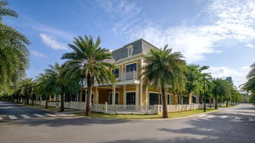 a yellow house with palm trees on a street at Wonderland Royal Mansions Ho Tram in Xuyên Mộc