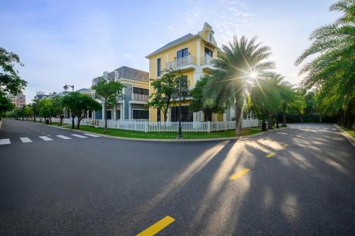 a yellow house on a street with palm trees at Wonderland Royal Mansions Ho Tram in Xuyên Mộc
