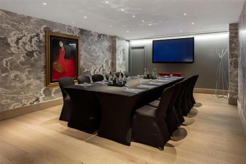 a conference room with a long table and black chairs at Radisson Blu Hotel, London Leicester Square in London