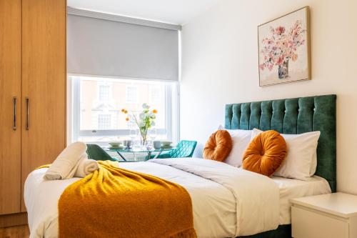a bedroom with a large bed with a green headboard at Kensington High Street Suites in London