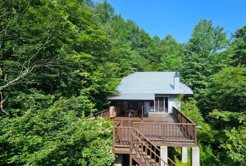 a house with a deck in the middle of trees at The Deck Villa KitaKaruizawa in Tsumagoi