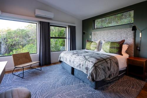 a bedroom with a large bed and two windows at Grootbos Private Nature Reserve in Gansbaai