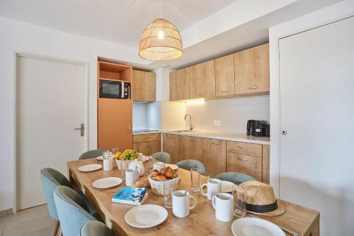a kitchen and dining room with a wooden table and chairs at Résidence Odalys Riviera in Hyères