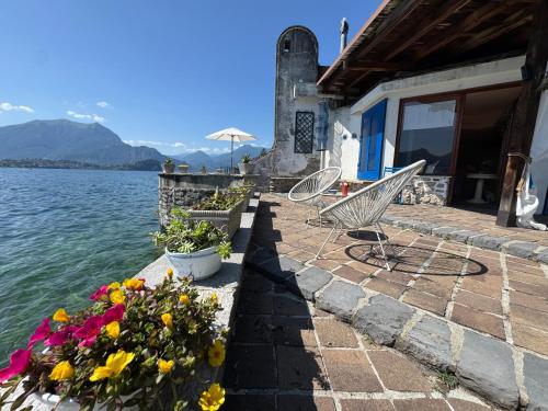 a patio with chairs and flowers on the water at Villa Planca by Gottschalk in Fiumelatte