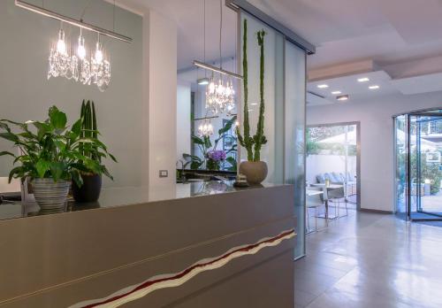 a lobby with a counter with potted plants and chandeliers at The One Hotel - Designed for Adults - Pet lovers in Riccione