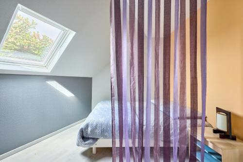 a bedroom with a bed and a curtain at Le Nid Marin - A 400m de la plage in Saint-Aubin-sur-Mer
