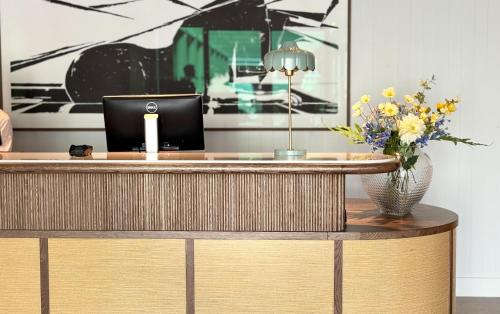 a desk with a laptop and a vase of flowers at Havna Tjøme Hotel in Tjøme
