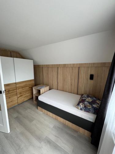 a small bedroom with a bed and wooden walls at Sóstó Suites in Nyíregyháza